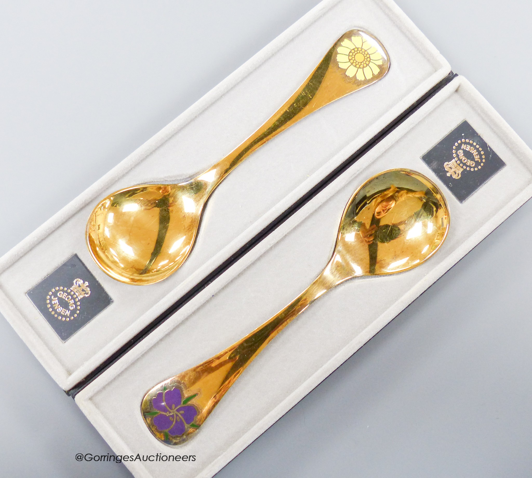 Two boxed Georg Jensen gilt sterling and enamel year spoons, 1973 & 1974 (Corn Marigold and Corn Cockle), 15cm, gross 91 grams.